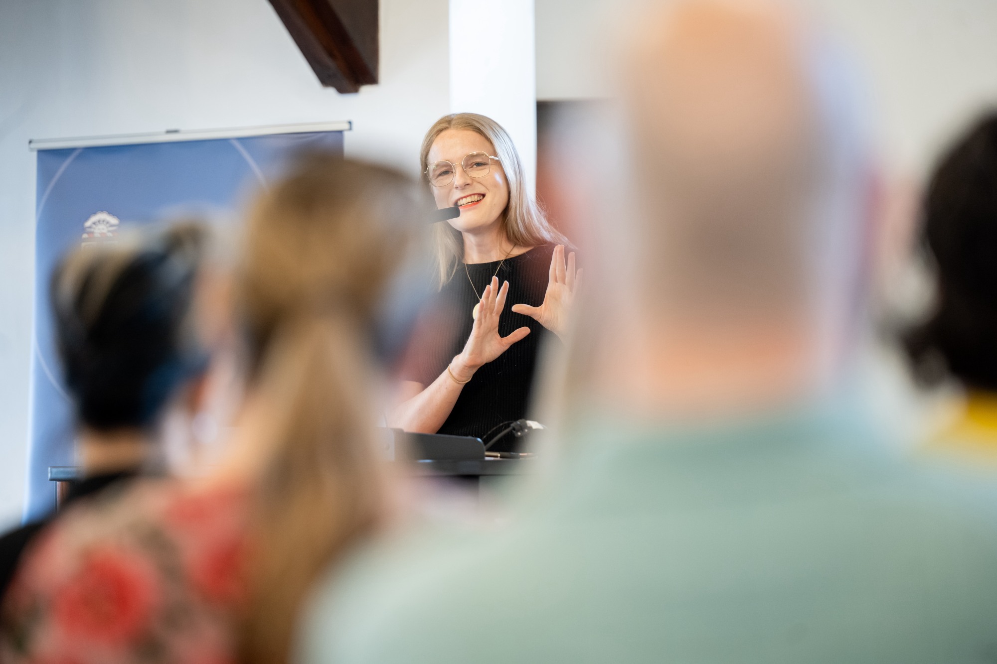 Gillian Branstetter speaks into a microphone and gestures.