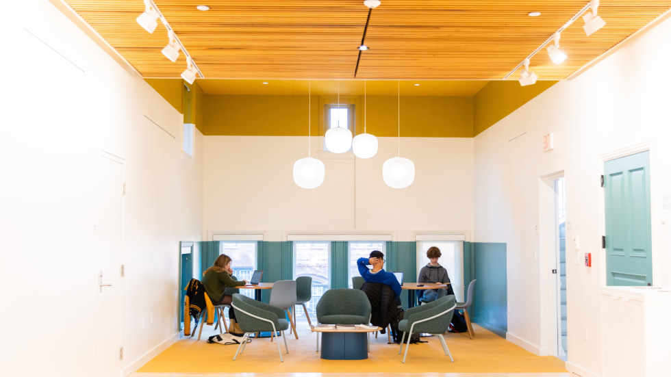 Students sit at small round tables in the second floor study lounge.