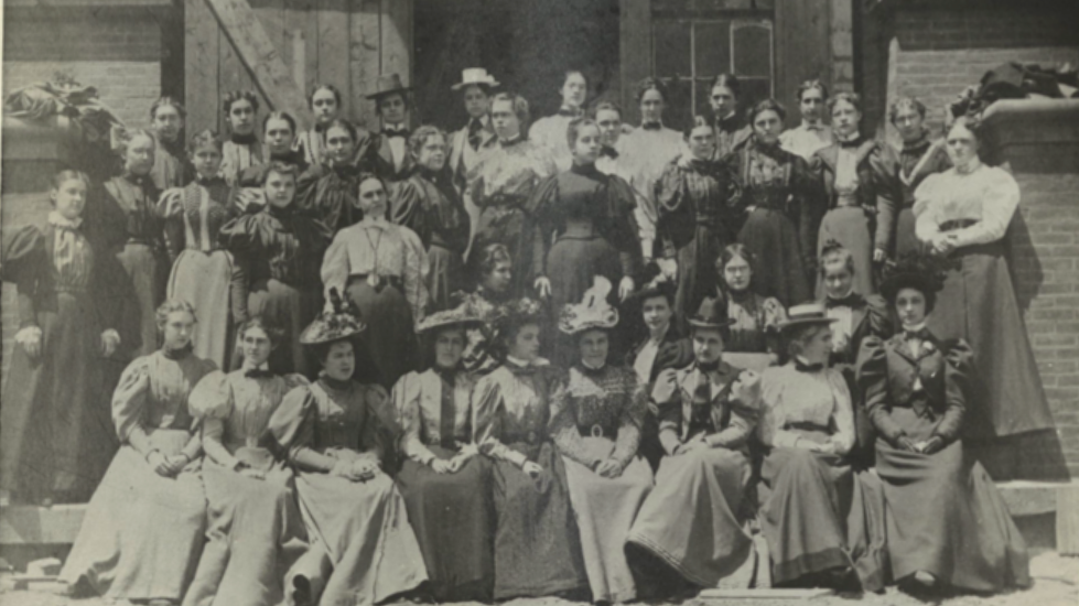 Black and white photograph shows the Women’s College class of 1900 standing in front of the unfinished Pembroke Hall.